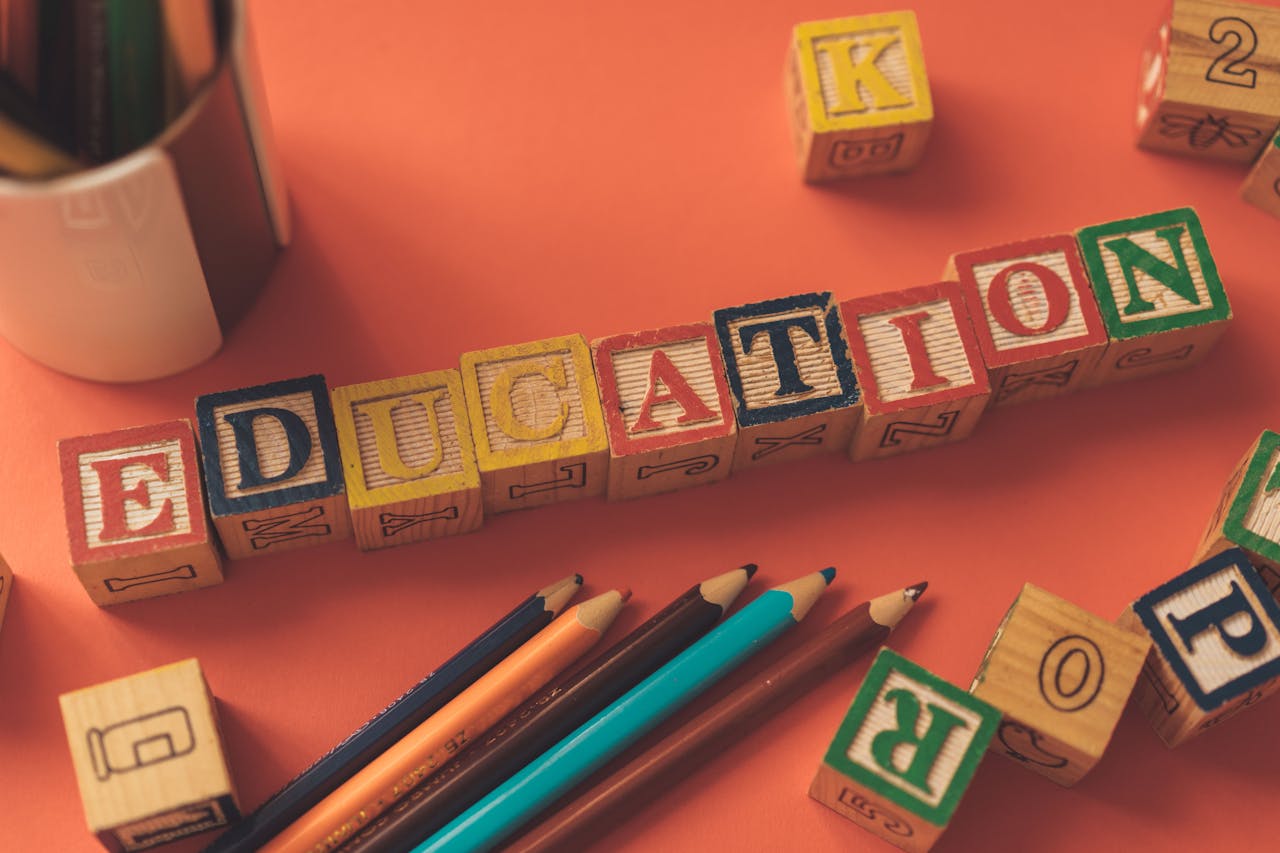 portfolio-02 Alphabet blocks spelling 'EDUCATION' on orange background with pencils.
