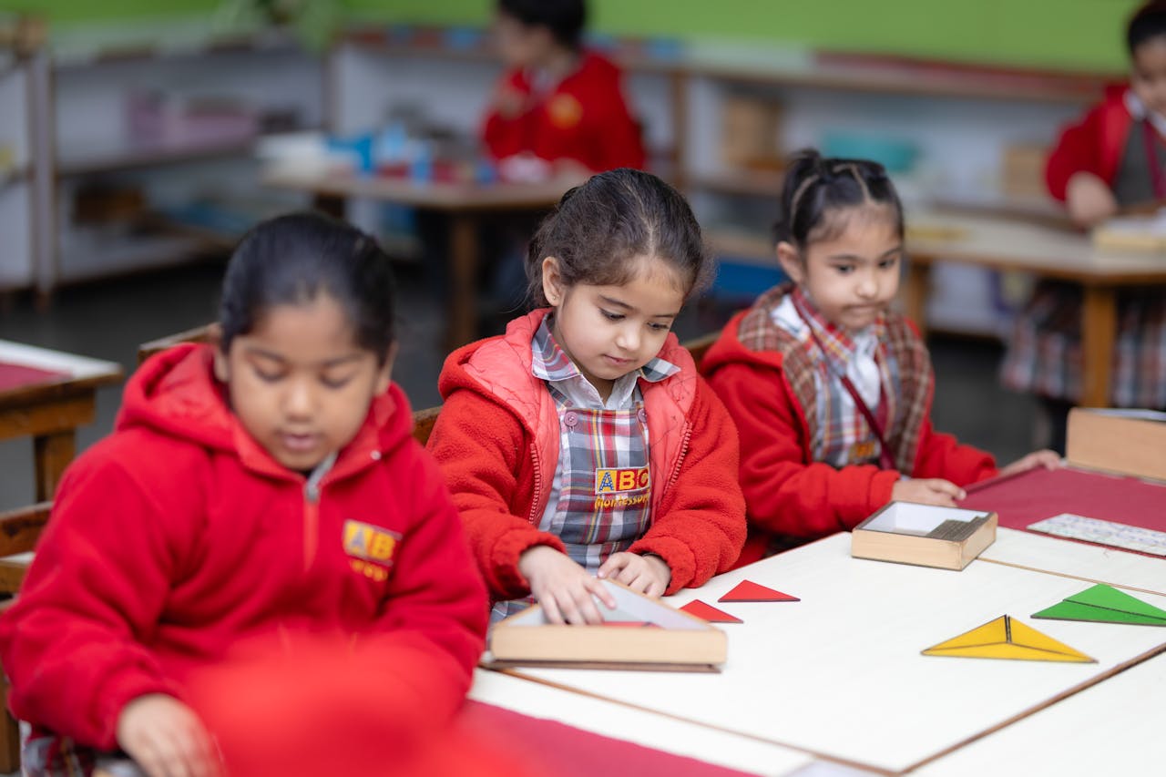 portfolio-06 Young children engaged in learning with educational tools in a Montessori classroom setting.