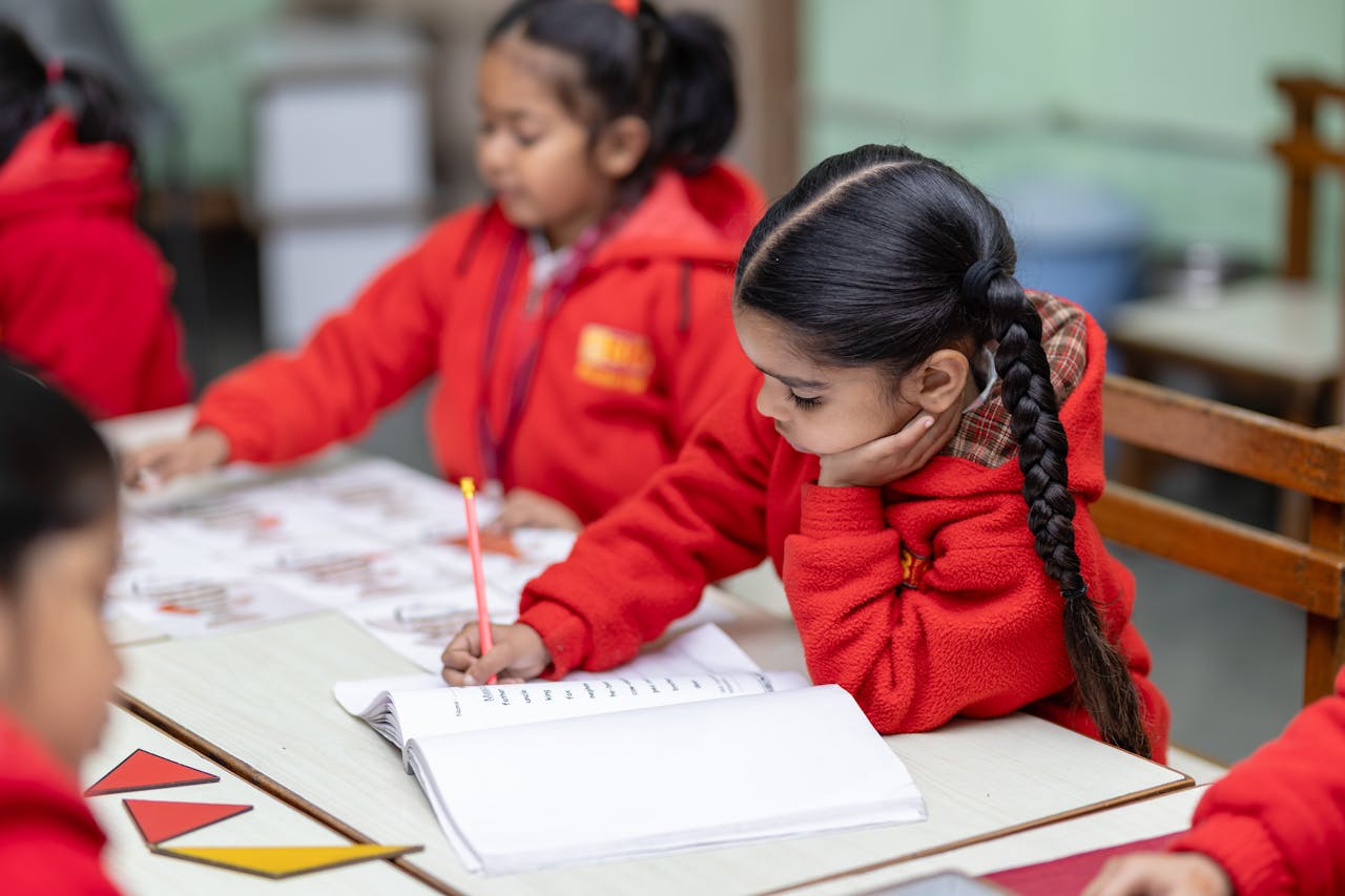 portfolio-04 Children in red uniforms focused on writing exercises at school desk.