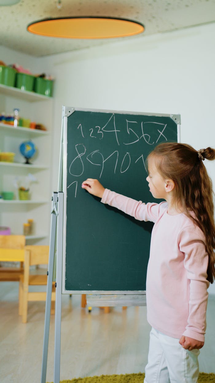 stats-img A girl engaging in educational learning by writing numbers on a chalkboard in a classroom.